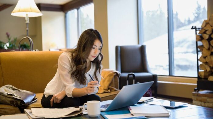 ey-businesswoman-working-at-laptop-in-lobby-900x505